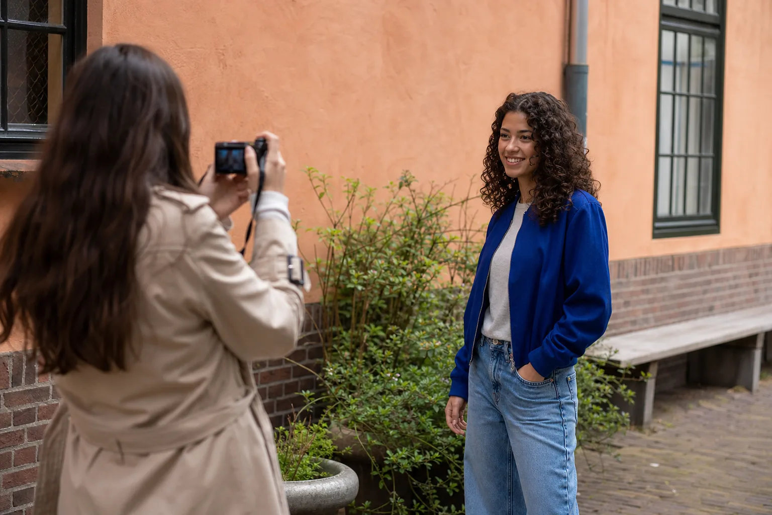 Vriendin fotografeert een jongvolwassene die ontspannen in een Nederlandse binnenplaats staat