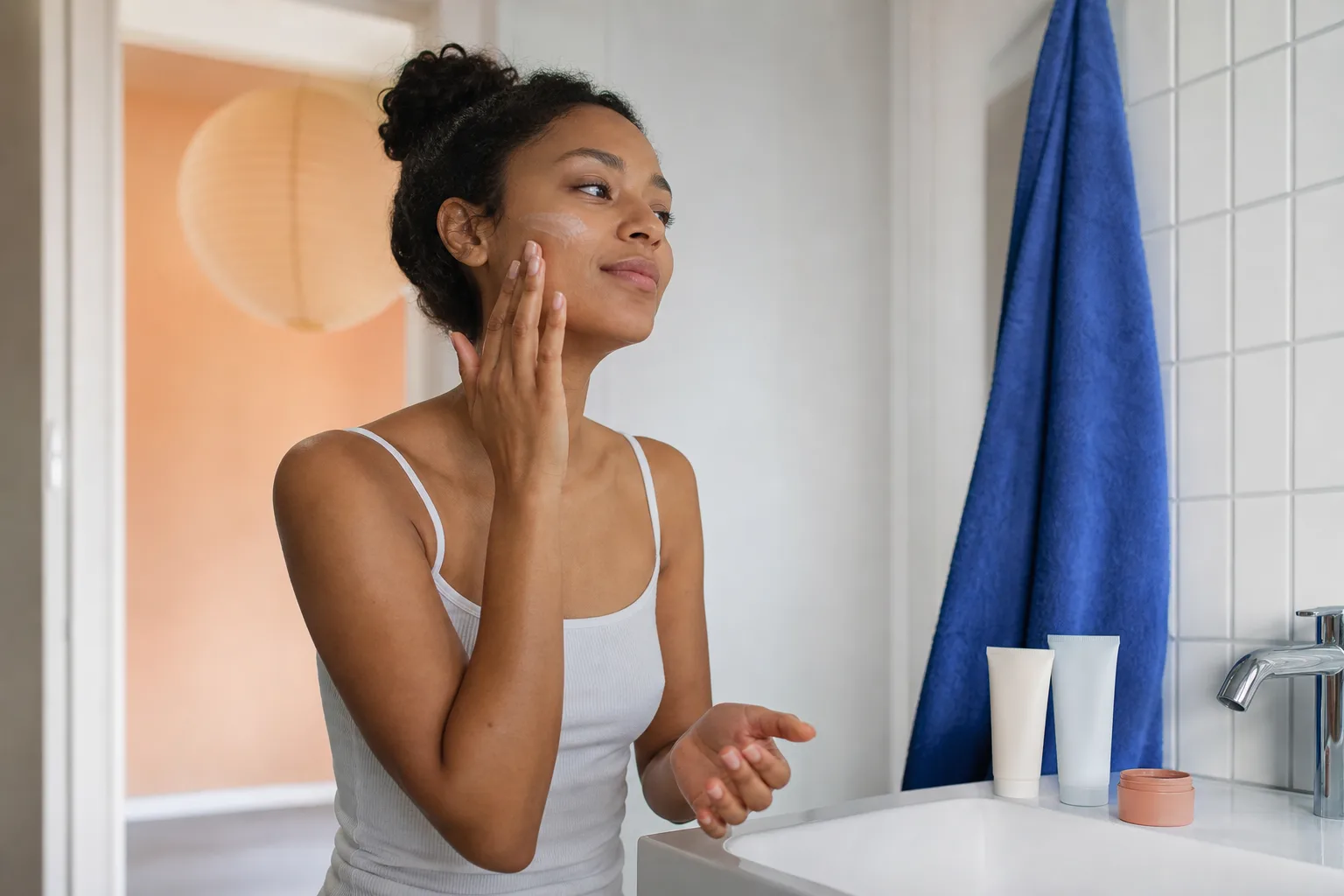 Jongvolwassene brengt moisturizer aan bij een eenvoudige wastafel